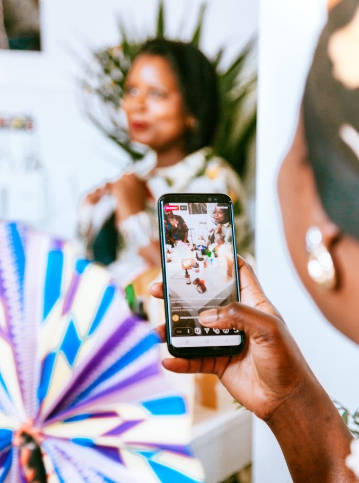Mastering the First Impression: Your intriguing post title goes here A person holds a smartphone capturing a live event with vibrant colors in the background.